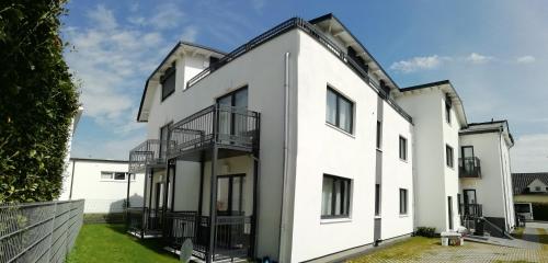 uma vista exterior para uma casa branca com uma varanda em Gepflegtes und schönes Ferienapartment im Neubau em Travemünde