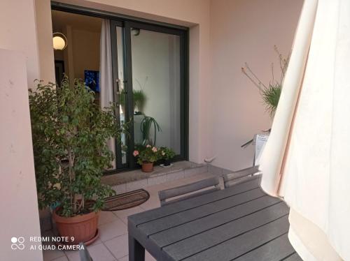 a porch with potted plants and a wooden bench at Casa del Parco in Olbia