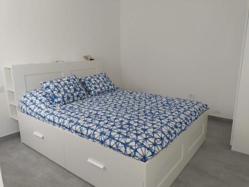 a white bed with blue and white sheets and pillows at Casa Blanca La Restinga in La Restinga