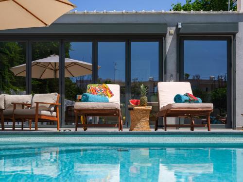 a swimming pool with chairs and an umbrella next to a pool at Villa Belle Helene Kalamaki Chania in Kalamaki Chanion