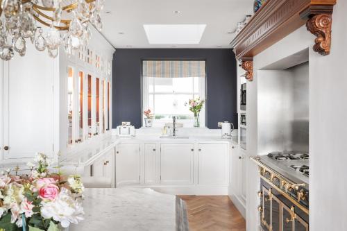 una cucina con armadi bianchi e lampadario pendente di Eastcliff House a Brighton & Hove