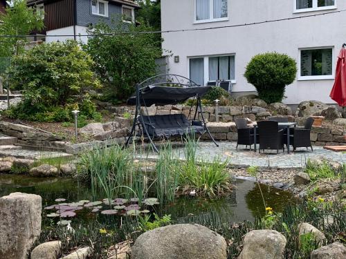 a garden with a pond with chairs and a swing at Hotel-Pension Teutonia in Braunlage