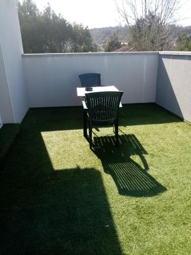 a patio with a table and a chair on the grass at Chez patou in Jezainville