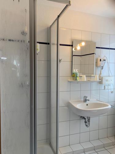 a bathroom with a shower and a sink and a mirror at Hotel-Pension Teutonia in Braunlage