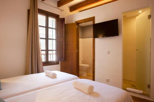 two beds in a room with a television and a bathroom at Casal de Petra - Rooms & Pool by My Rooms Hotels TI in Petra