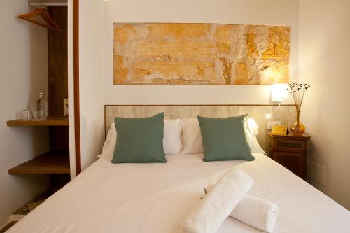 a bedroom with a white bed with green pillows at Casal de Petra - Rooms & Pool by My Rooms Hotels TI in Petra