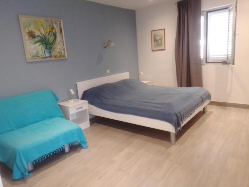 een slaapkamer met een bed met een blauwe deken en een raam bij Apartments Haracic in Hvar