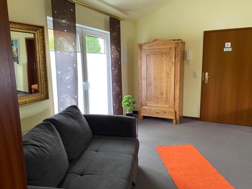 a living room with a black couch and a door at Hotel-Pension Teutonia in Braunlage