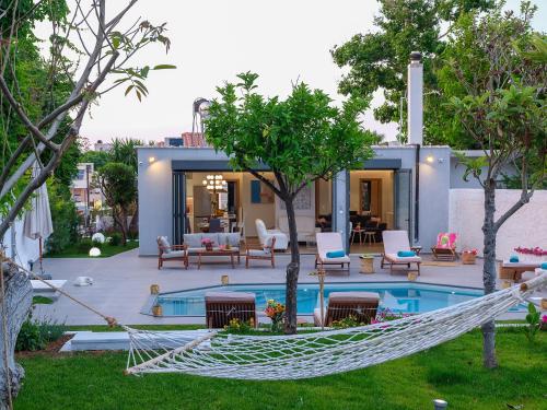 a hammock in front of a house with a pool at Villa Belle Helene Kalamaki Chania in Kalamaki Chanion