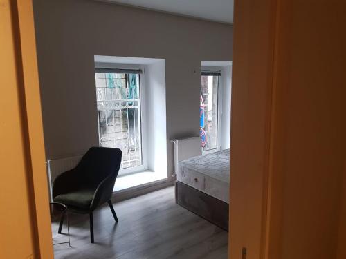 a room with a chair and a bed and two windows at D and D hotel in Tbilisi City