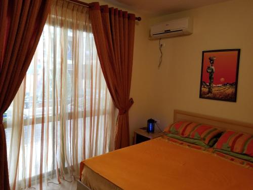 um quarto com uma cama e uma grande janela em Apartament Emiri Golem em Golem