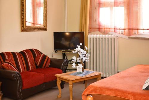 a living room with a couch and a tv at Hotel-Pension Teutonia in Braunlage