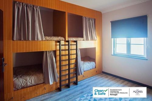 two bunk beds in a room with a window at D. Irene Hostel in Lajes
