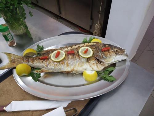 un pesce con fette di limone su un piatto su un bancone di Samothraki Akrogiali Rooms a Samotracia