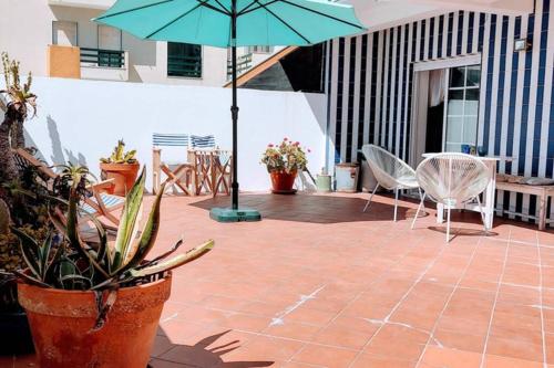 a patio with a table and chairs and an umbrella at CASA DA ZECA, GARAGEM GRATUITA, COSTA NOVA in Gafanha da Encarnação
