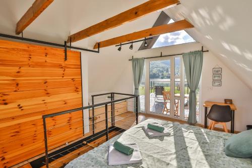 a bedroom with a bed and a desk and a balcony at Vila Kosjenka on lake Sabljaci in Ogulin