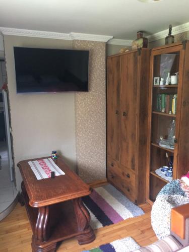 ein Wohnzimmer mit einem Tisch und einem Flachbild-TV in der Unterkunft Апартаменты PAROSTKI in Swaljawa