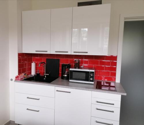 cocina blanca con microondas y pared de ladrillo rojo en La Petite Trier, en Trier