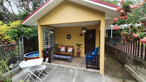 a small yellow house with chairs and a table at Plantacion Isabelle in Taal
