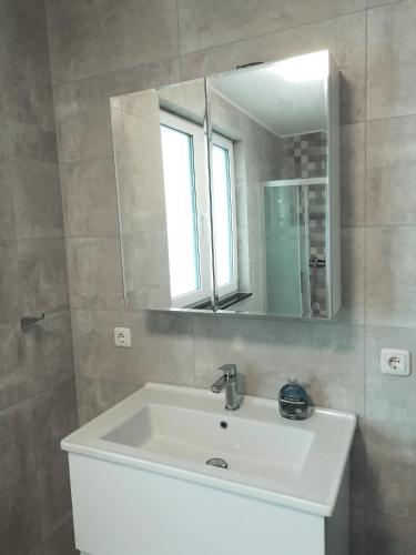ein Badezimmer mit einem weißen Waschbecken und einem Spiegel in der Unterkunft Gepflegtes und schönes Ferienapartment im Neubau in Travemünde