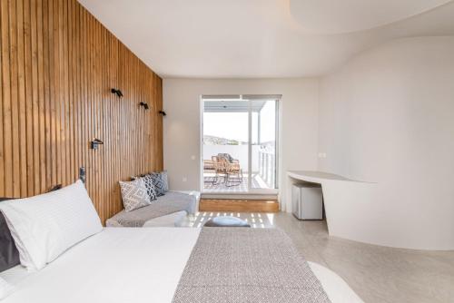 a bedroom with a bed and a desk and a window at Onar Hotel & Suites in Tinos Town