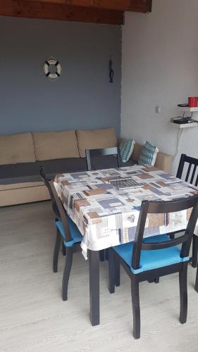 een tafel en stoelen in een woonkamer met een bank bij cap coudalere in Le Barcarès