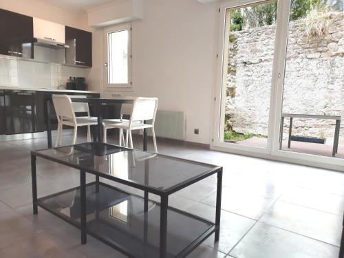 uma sala de estar com uma mesa de vidro e cadeiras brancas em kérentrée - Appartement en centre ville avec terrasse et parking privé em Pont-lʼAbbé