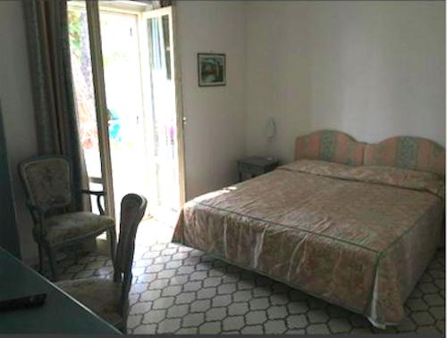 a bedroom with a bed and a desk and a chair at Hotel Poseidon in Diamante