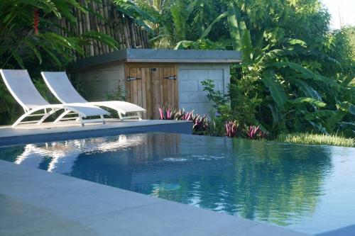 duas cadeiras sentadas ao lado de uma piscina em Villa Kumquat, avec piscine Clévacances 4 clés em Petit-Bourg
