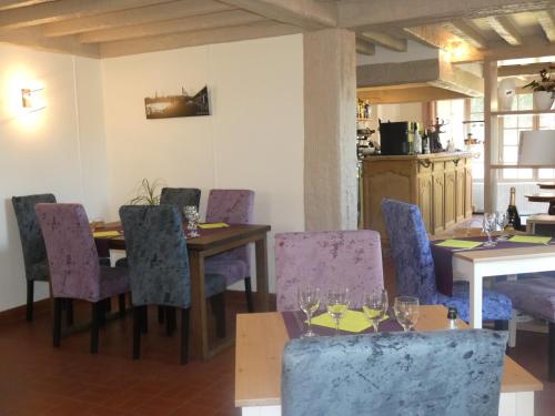 a dining room with purple chairs and a table with wine glasses at Logis Hôtel Restaurant Auberge Saint Martin in Surville