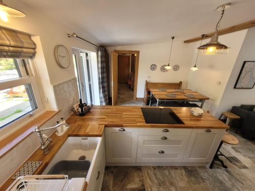 eine Küche und ein Wohnzimmer mit einem Waschbecken und einem Tisch in der Unterkunft Loch Lomond Blair Byre in Rowardennan