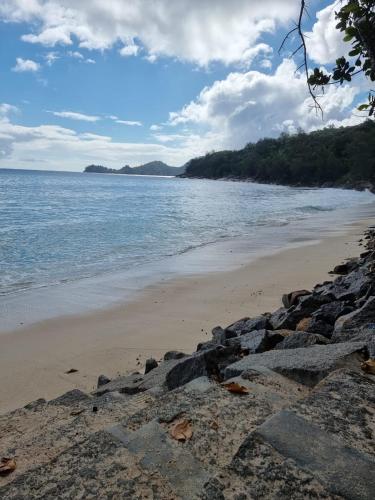 a beach with rocks and the ocean on a cloudy day at Chalets Des Vacances in Takamaka
