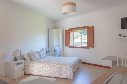 a white bedroom with a bed and a window at Cantinho da Quintã in Mesão Frio