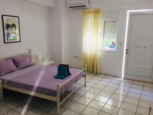 um quarto com uma cama roxa e uma janela em Korona beach apartments III em Rethymno Town