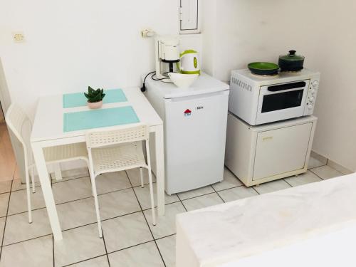 uma cozinha com uma mesa branca e um micro-ondas em Korona beach apartments III em Rethymno Town
