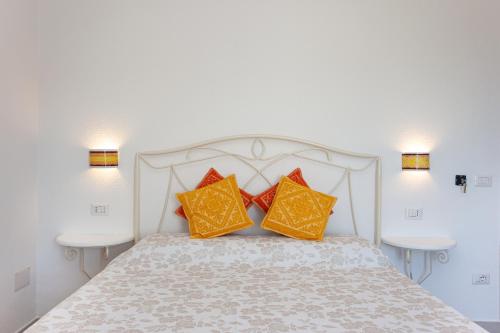 a white bed with two orange pillows on it at La Casa in Collina - affittacamere con vista mare in Lu Lioni