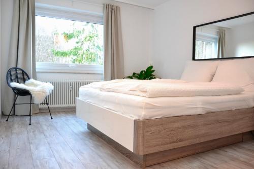 1 dormitorio con 1 cama, 1 silla y 1 ventana en VIVID - Deluxe Apartment in idealer Lage mit Bergblick, en Bad Harzburg