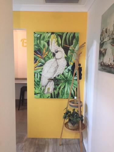 a painting of a parrot on a yellow wall at Stylish Colourfull Getaway in Margaret River Town