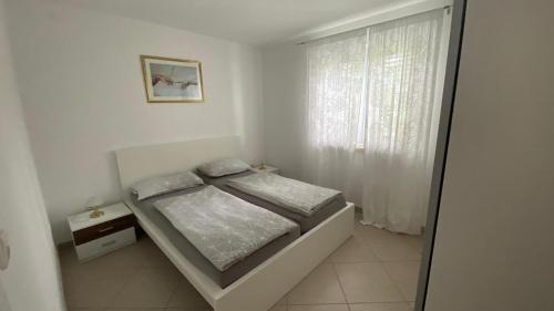 biała sypialnia z łóżkiem i oknem w obiekcie Vila Luca island KRK / Malinska w mieście Malinska