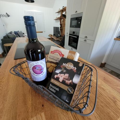 a bottle of wine in a basket on a table at Loch Lomond Blair Byre in Rowardennan