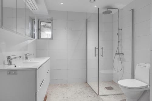 a white bathroom with a shower and a toilet at 4 Bedroom Archipelago Retreat in Tranholmen
