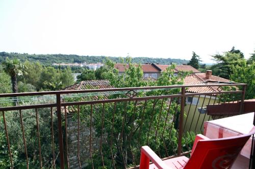 Un balcón con una silla roja y vistas. en Rooms Torcello - with shared bathroom, en Portorož