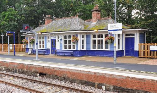 a blue and white train station with a train at 131 on Atholl in Pitlochry