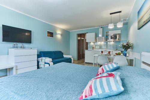 a blue bedroom with a bed and a kitchen at Apartament Słoneczny in Świnoujście
