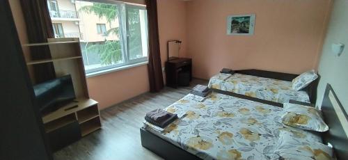 a bedroom with two beds and a tv in it at Къща, стаи за гости Мери in Chernomorets