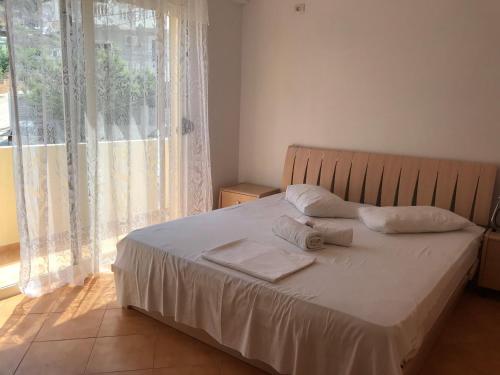 a bedroom with a bed with two pillows and a window at Olive Tree in Sarandë