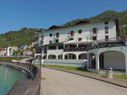 un grand bâtiment blanc à côté d'une étendue d'eau dans l'établissement Hotel Celis, à Barcis