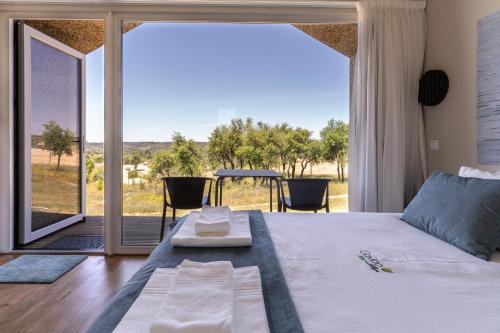 1 dormitorio con 1 cama y una gran ventana de cristal en Gavião Nature Village, en Gavião