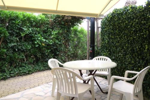 une table blanche et des chaises assises sous un parasol dans l'établissement Naturiste Cap d'Agde Villa Héliovillage 12, au Cap d'Agde