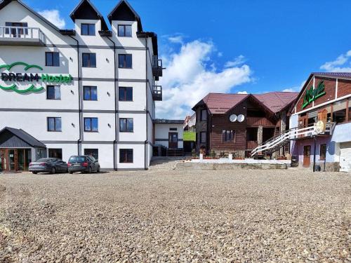 a large white building with cars parked in a parking lot at MAFA Apartaments in Bukovel
